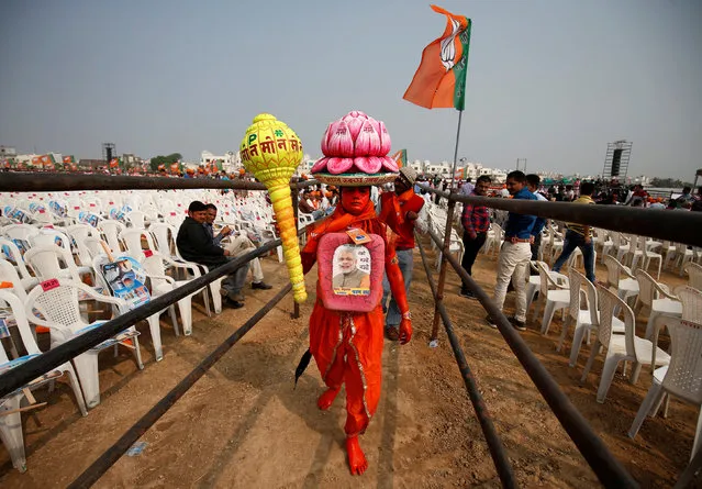 A supporter carries overhead a model of lotus, the election symbol of India's ruling Bharatiya Janata party (BJP), as he arrives to attend a campaign meeting addressed by Prime Minister Narendra Modi ahead of Gujarat state assembly election in Kalol on the outskirts of Ahmedabad, India, December 8, 2017. (Photo by Amit Dave/Reuters)