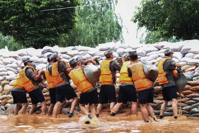This photo taken on July 14, 2020 shows Chinese soldiers building an emergency levee near the Poyang Lake to contain flooding due to torrential rains in Jiujiang in China's central Jiangxi province. The vast Yangtze drainage area has been lashed by torrential rains since last month, leaving 141 people dead or missing and forcing the evacuation of millions more across several provinces. (Photo by AFP Photo/China Stringer Network)
