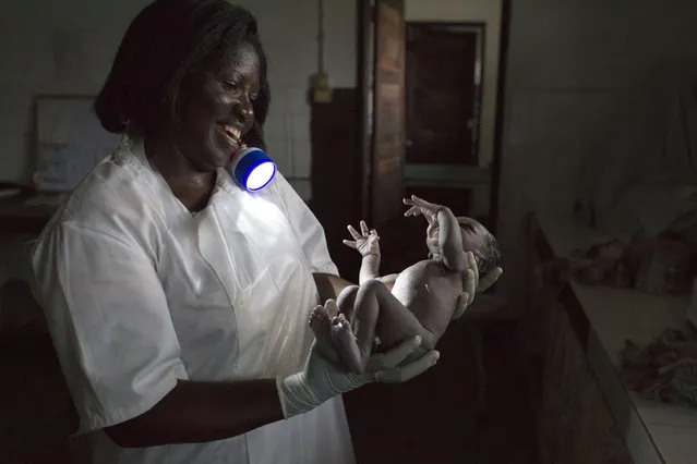 In this May 23, 2012 file photo, chief midwife Maria Antoneta Cabral Barbosa holds a newborn baby boy she had just delivered by flashlight, at the regional hospital in Gabu, Guinea-Bissau. In Guinea-Bissau, one of the deadliest places in the world to give birth, a woman has a 1 in 19 chance of maternal death, compared to about 1 in 2,100 in the United States. Experts say women are increasingly heading to medical centers when things go awry, but logistical, financial, and cultural barriers are still keeping many pregnant women from seeking help in time. (Photo by Rebecca Blackwell/AP Photo)