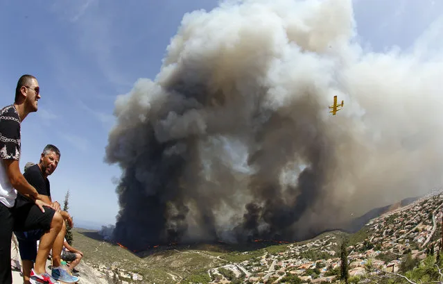 People look at a wildfire burning nearby Benitachel village, eastern Spain, Monday, September 5, 2016. (Photo by Alberto Saiz/AP Photo)