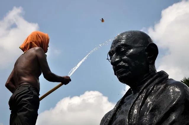 A butterfly flutters as an Indian labourer showers water onto a statue of Mahatma Gandhi on the eve of Gandhi Jayanti at Gandhi Park in the eastern city Bhuabenswar on October 1, 2015. Gandhi Jayanti is also observed as International Day of Non-Violence and is celebrated in India to mark the occasion of the birth anniversary of Mahatma Gandhi, the Father of the Nation on October 2 annually. (Photo by Asit Kumar/AFP Photo)