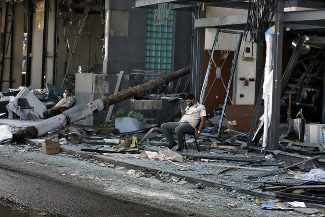 Security personnel sit in front of damaged buildings near the site of an explosion on Tuesday that hit the seaport of Beirut, Lebanon, Thursday, August 6, 2020. The blast which appeared to have been caused by an accidental fire that ignited a stockpile of ammonium nitrate at the port, rippled across the Lebanese capital, killing at least 135 people, injuring more than 5,000 and causing widespread destruction. (Photo by Bilal Hussein/AP Photo)