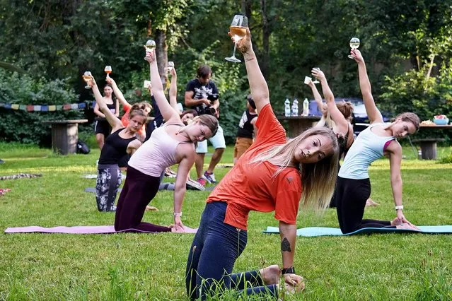 People participate in a special yoga exercise with glasses of wine in their hands in Riga, Latvia on August 8, 2020. (Photo by Xinhua News Agency/Rex Features/Shutterstock)