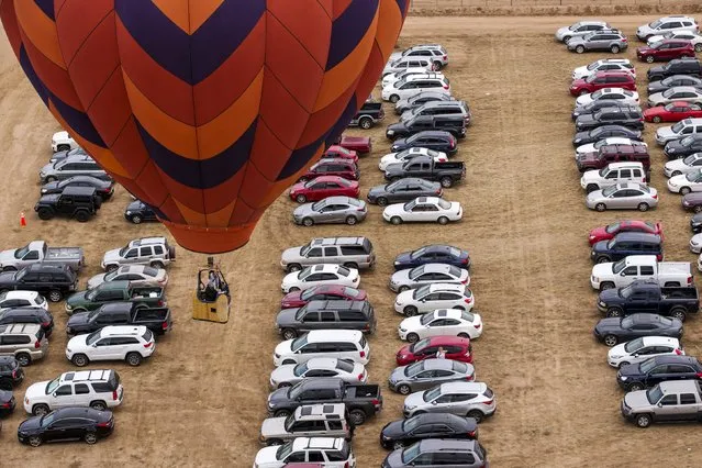 A hot air balloon floats over a parking lot during the 2015 Albuquerque International Balloon Fiesta in Albuquerque, New Mexico, October 4, 2015. (Photo by Lucas Jackson/Reuters)
