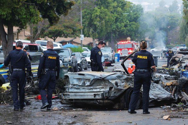 Emergency personnel work at the crash scene on a street, after a small civilian aircraft went down in a military neighborhood in San Diego, California on May 22, 2025. (Photo by Mike Blake/Reuters)