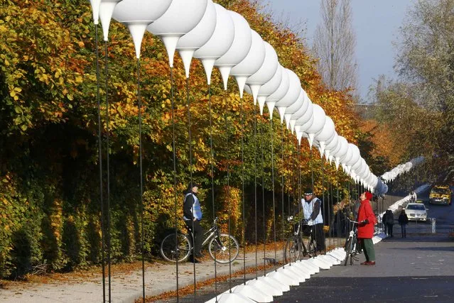 People look at stands with balloons placed along the former Berlin Wall location at Mauerpark, which will be used in the installation “Lichtgrenze” (Border of Light) in Berlin November 7, 2014. (Photo by Pawel Kopczynski/Reuters)