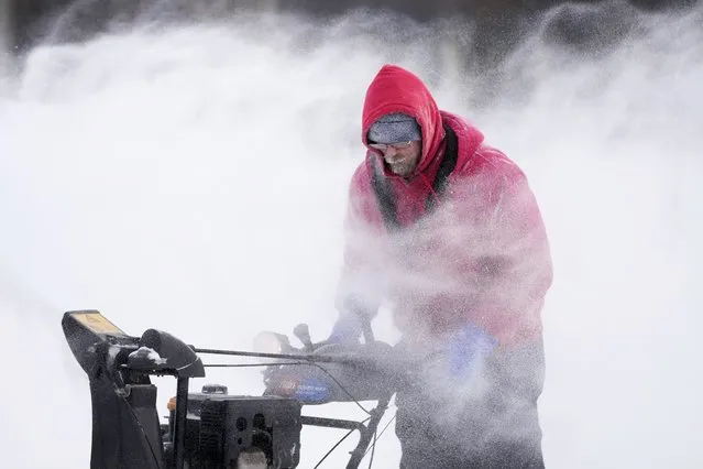 Mark Sorter clears snow from a downtown ice skating rink, Friday, December 23, 2022, in Des Moines, Iowa. (Photo by Charlie Neibergall/AP Photo)