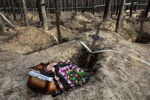 This photograph shows a empty coffin after the exhumation of bodies in the mass graves dug during the Russian occupation in the city of Izium, eastern Ukraine on January 2, 2023. Izium was captured by Russian forces, after the takeover by Ukrainian troops, torture chambers were discovered, and in the nearby forest more than 440 graves and a mass grave were found. The remains were all exhumed for identification and to determine the cause of death, as Ukrainian authorities suspect war crimes. (Photo by Sameer Al-Doumy/AFP Photo)