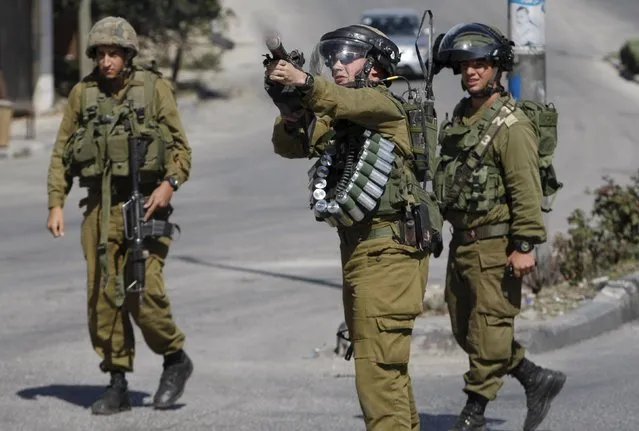 An Israeli soldier fires a tear gas canister at Palestinian protesters during clashes in the West Bank city of Hebron October 13, 2015. Seven Israelis and 27 Palestinians, including nine alleged attackers and eight children, have died in almost two weeks of street attacks and security crackdowns.The violence has been stirred in part by Muslim anger over increasing Jewish visits to the al-Aqsa mosque compound in Jerusalem, Islam's holiest site outside the Arabian Peninsula. (Photo by Mussa Qawasma/Reuters)