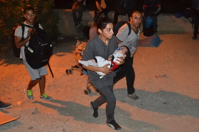 Migrants flee from the camp of Moria on Lesvos island, Greece, 19 September 2016. Migrants set fire to several parts of the camp which then spread causing hundreds of people to flee. Authorities evacuated the area where unaccompanied minors were living and transferred them to a new facility.Earlier today, rumours that mass returns to Turkey were imminent prompted renewed incidents and a break-out from the hotspot who attempted to set off on a protest march to Mytilene, the island's main town, but were stopped and forced to turn back by police. (Photo by Stratis Balaskas/EPA)