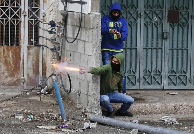 A Palestinian protester releases fireworks during clashes with Israeli troops in the West Bank town of Abu Dis near Jerusalem November 17, 2014. A Palestinian bus driver was found hanged inside his vehicle on Monday, an incident Israeli police described as a suicide but which the driver's family said they believed was an attack. (Photo by Ammar Awad/Reuters)