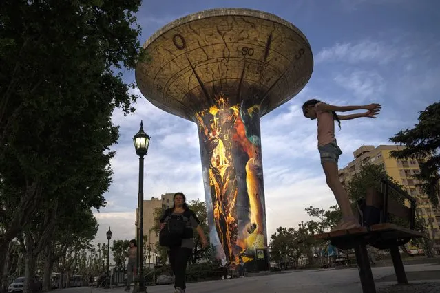 A water tank towers over the town's public square in Monte Grande, Argentina, Friday, October 28, 2022. The enormous water tank became a work of art in 2020 when, at the municipality's request, artist Leandro García Pimentel painted a mural on it depicting fire, earth, air and water. (Photo by Rodrigo Abd/AP Photo)