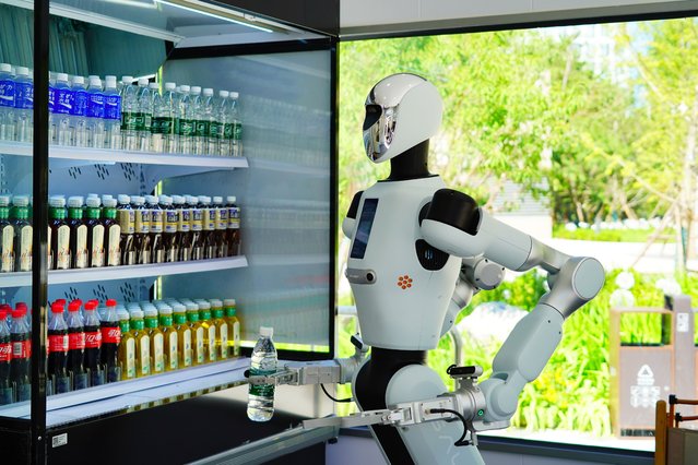 A Galbot humanoid robot salesperson delivers a drink for a customer at the 9-square-meter bus shop in ART PARK on August 10, 2025 in Beijing, China. Galbot, the developer of the robot, plans to establish 100 stores across 10 cities in China this year, with expectations of serving up to 2,000 customers per store every day. (Photo by Song Jiaru/VCG via Getty Images)
