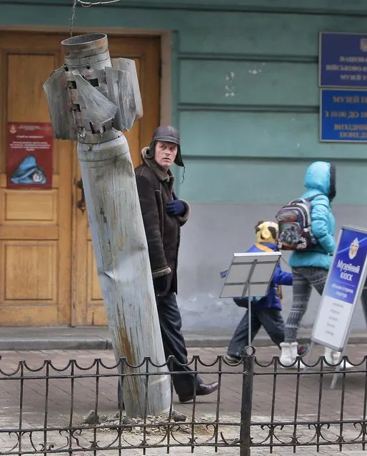 People pass by an unexploded missile shot by pro-Russian separatists in the country's east and brought to the Ukrainian capital as a symbol of the current conflict, in downtown Kiev, Ukraine, Tuesday, December 16, 2014. (Photo by Efrem Lukatsky/AP Photo)