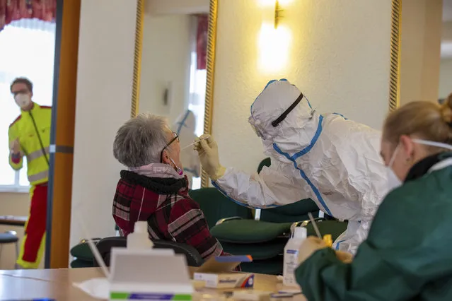 A man in a protective suit takes a sample for a corona virus test from an older woman in Rathmannsdorf, Germany, Friday, December 4, 2020. The inhabitants of the community of Rathmannsdorf in the federal state Saxonia tested for the corona virus. The Saxon State Ministry for Social Affairs and Social Cohesion (SMS) wants to use this campaign to gain knowledge about the spread of the virus in five selected districts. (Photo by Daniel Schaefer/dpa via AP Photo)