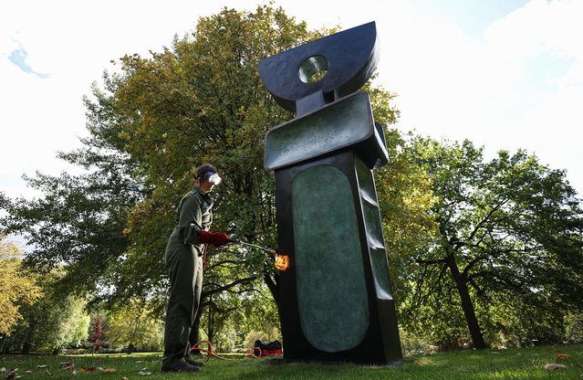 Conservator Lowri Morris undertakes re-patination work on “Ultimate Form”, part of the “Family of Man” series by renowned British artist Barbara Hepworth at the Yorkshire Sculpture Park in Wakefield, Britain, 23 September 2025. The Family of Man is a series of nine bronze figures made in 1970 as one of the last major works before Barbara Hepworth's death in 1975. (Photo by Adam Vaughan/EPA)