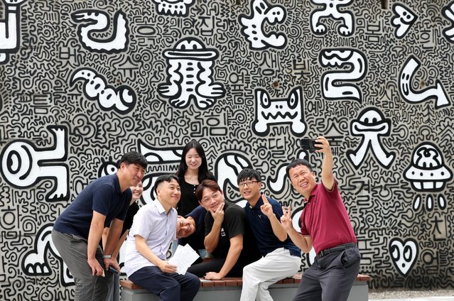 Visitors take commemorative photos in front of the large mural “HANGOODLE” by Mr. Doodle, a world-renowned British drawing artist, on the September 16, 2025. Installed on the wall of the former Shiniljesa building in downtown Sejong City, the artwork combines Korean words suggested by citizens with the artist's signature symbols and icons. (Photo by Shin Hyeon-jong)