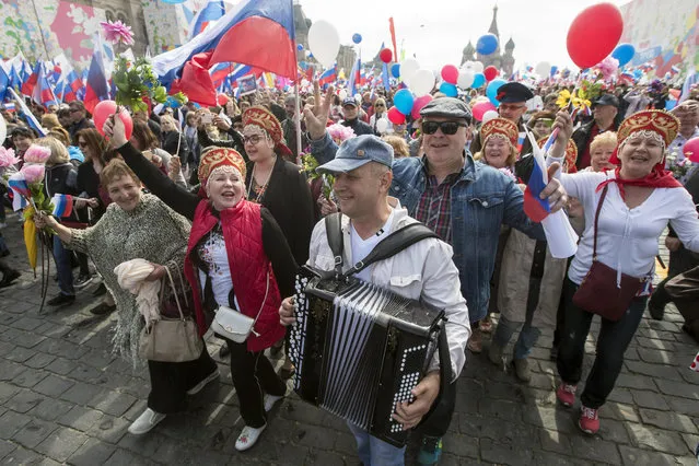 Russians wave flags and sing songs as they walk on Red Square to mark May Day in Moscow, with St. Basil's Cathedral in the background, Russia, Tuesday, May 1, 2018. (Photo by Pavel Golovkin/AP Photo)