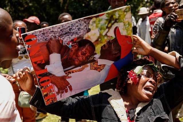 A mourner holds a photo of Kenyan opposition leader Raila Odinga hugging someone as she gathers with others at Odinga's residence in the Karen neighbourhood of Nairobi on October 15, 2025 following the death of Odinga at the age of 80 during a health visit to India. Kenyan opposition leader Raila Odinga has died at the age of 80 during a health visit to India, local police said on October 15, 2025 Odinga was the perennial opposition figure of Kenyan politics, running unsuccessfully for the presidency on five occasions, most recently in 2022. .He remained a dominant force, able to rally huge numbers, particularly from his native western Kenya. (Photo by Simon Maina/AFP Photo)
