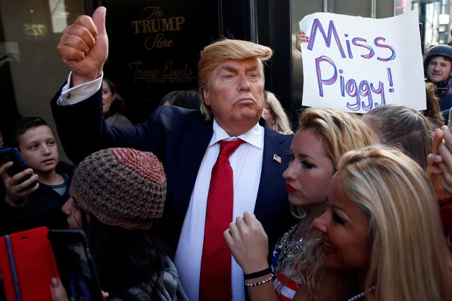 A man dressed as U.S. Republican candidate Donald Trump gives the thumbs with bikini clad women as part of a performance piece by British author and artist Alison Jackson outside Trump Tower in New York, U.S., October 25, 2016. (Photo by Shannon Stapleton/Reuters)
