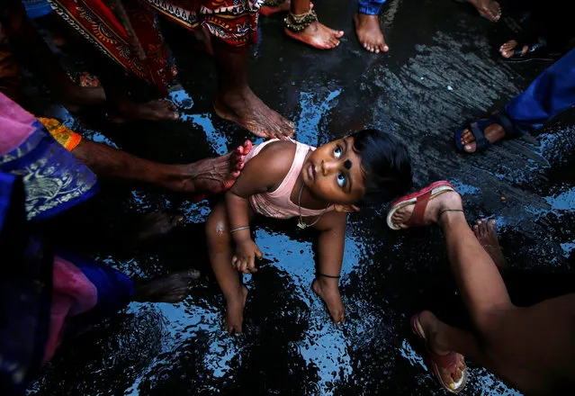Hindu devotees (not pictured) touch a child with their feet as part of a ritual to bless him during a religious procession held to mark the Gajan festival in Kolkata, India, April 13, 2018. (Photo by Rupak De Chowdhuri/Reuters)