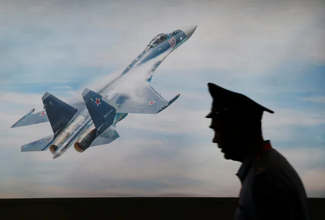 A military personnel member walks past a picture of Sukhoi jet fighter during Indo Defence Expo in Jakarta, Indonesia November 2, 2016. (Photo by Reuters/Beawiharta)