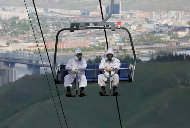 Employees of the Derate pest control company use a ski lift as they move uphill to spray pesticide to kill ticks carrying encephalitis at the Bobrovy Log resort area in Taiga district outside Krasnoyarsk, Russia May 30, 2018. (Photo by Ilya Naymushin/Reuters)