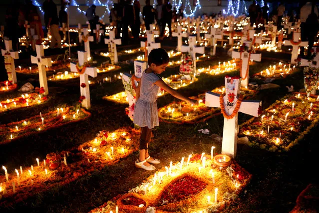 A child lays flowers on the grave of her relatives before praying at a cemetery during the observance of All Souls Day in Dhaka, Bangladesh, November 2, 2016. (Photo by Mohammad Ponir Hossain/Reuters)