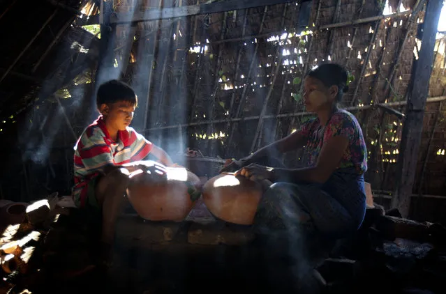 A boy helps his mother to make earthen pots at their home factory Sunday, November 22, 2015, in Twantay township on the outskirts of Yangon, Myanmar. (Photo by Khin Maung Win/AP Photo)