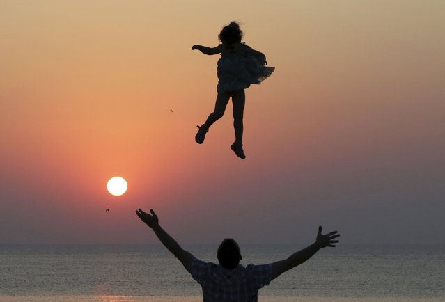 A man throws a girl into the air during sunset as they spend time on the territory of Chersonesus Tavrichesky (Tauric Chersonesos) National Reserve in the Black Sea port of Sevastopol, Crimea, Ukraine, July 25, 2015. (Photo by Pavel Rebrov/Reuters)