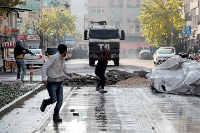 A demonstrator throws stones at a police vehicle during a protest against the curfew in Sur district, in the southeastern city of Diyarbakir, Turkey, December 18, 2015. (Photo by Sertac Kayar/Reuters)