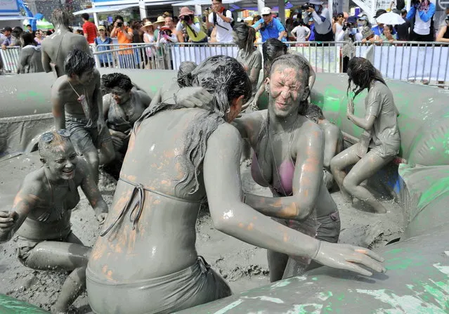 Tourists play with mud during the 16th Boryeong mud festival at Daecheon swimming beach in Boryeong, 150 kilometers southwest of Seoul, on July 20, 2013. The annual festival which runs from July 19-28 aims to encourage the use of mud for cosmetic skin-care and to promote tourism in the region. (Photo by Jung Yeon-Je/AFP Photo)