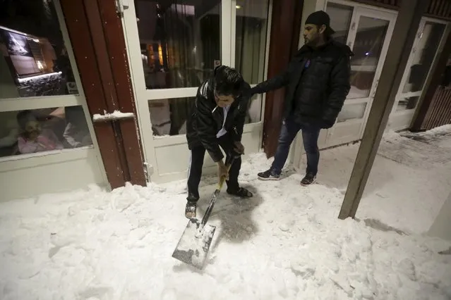 A refugee clears snow at the entrance of a camp at a hotel touted as the world's most northerly ski resort in Riksgransen, Sweden, December 15, 2015. (Photo by Ints Kalnins/Reuters)