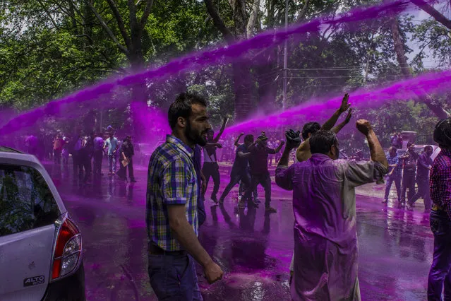 Indian police fire a jet of dyed water from their water cannon at Kashmiri government teachers during a protest against the government on July 17, 2018 in Srinagar, the summer capital of Indian Administered Kashmir, India. Hundreds of Kashmir government teachers took to the streets in the city centre to demand an increase in their salaries. Indian police used purple dyed water canons to disperse them. (Photo by Yawar Nazir/ Getty Images)