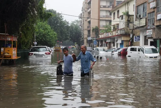 Peoepl walk through a flooded street after heavy rains in New Delhi, India on July 8, 2023. (Photo by Anushree Fadnavis/Reuters)