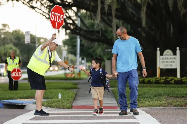 Crossing guard Tony Pinion, left, gives a fist bump to Andrés Cantero, 4, while his father, Angel Cantero, 48, both of Carrollwood, walks him to school during the first day of class at Carrollwood K-8 School on Thursday, August 10, 2023, in Tampa, Fla. (Photo by Jefferee Woo/Tampa Bay Times via AP Photo)