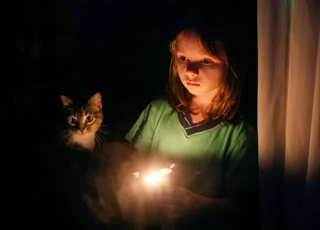 A girl is seen in a window as she holds a candle during a commemoration for Holodomor victims marking the 83rd anniversary of the famine of 1932-33 in which millions died of hunger, in Kiev, Ukraine, November 26, 2016. (Photo by Gleb Garanich/Reuters)