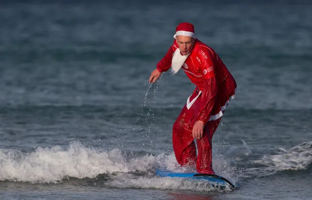 A surfer gets to his feet as he braves the cold seas and near flat waves during the annual Surfing Santa as part of the Santa Run and Surf 2016 at Fistral Beach in Newquay on December 4, 2016 in Cornwall, England. (Photo by Matt Cardy/Getty Images)