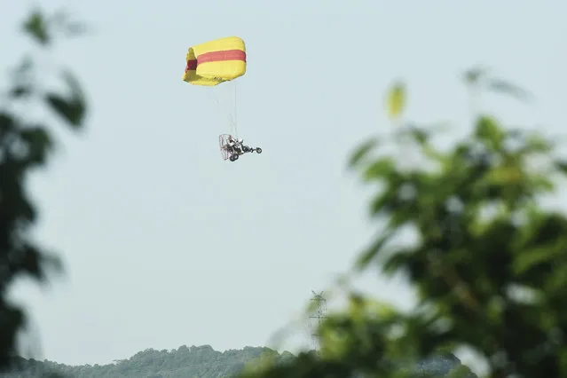 A worker in a powered parachute searches for a runaway leopard in Hangzhou in eastern China's Zhejiang province Sunday, May 9, 2021. (Photo by Chinatopix via AP Photo)
