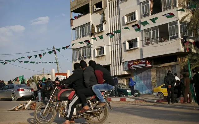 Palestinians on a motorcycle watch Hamas militants as they rappel down a building during a rally in support of what organizers said is a Palestinian uprising against Israel, in Beit Lahiya town in the northern Gaza Strip January 22, 2016. (Photo by Suhaib Salem/Reuters)