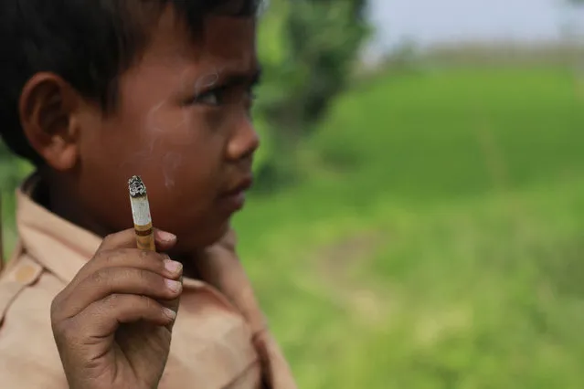 Seven-year-old Dihan Awallidan from Garut, West Java, is not like other boys his age. While most children crave chocolate and candy, Dihan is addicted to cigarettes. The second-grader picked up the habit at the age of 3 and now smokes up to three packs a day, using the pocket money he gets from his enabling parents to feed his addiction. (Photo by Rezza Estily/JG Photo)