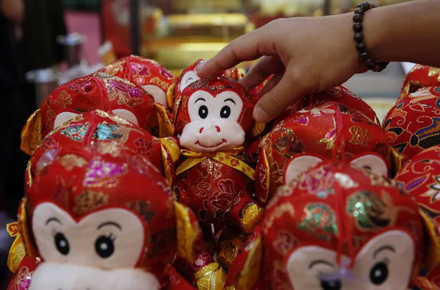A shop assistant rearranges toy monkeys for sale ahead of the Chinese New Year, the year of the monkey, in Kuala Lumpur, Malaysia, February 4, 2016. (Photo by Olivia Harris/Reuters)