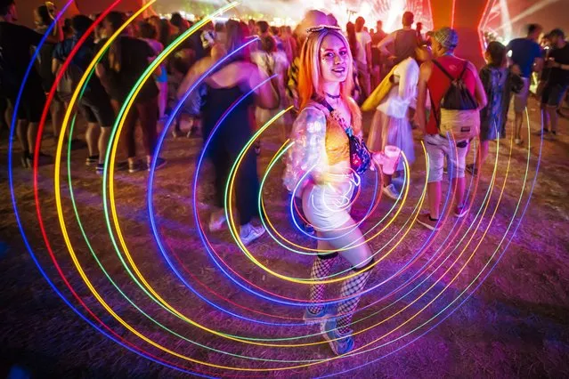 A festival goer spins a light strip as she dances to electronic music in front of the Belleville stage during the 45th edition of the Paleo Festival, in Nyon, Switzerland, 24 July 2022. The Paleo is the largest open-air music festival in the western part of Switzerland. (Photo by Valentin Flauraud/EPA/EFE)