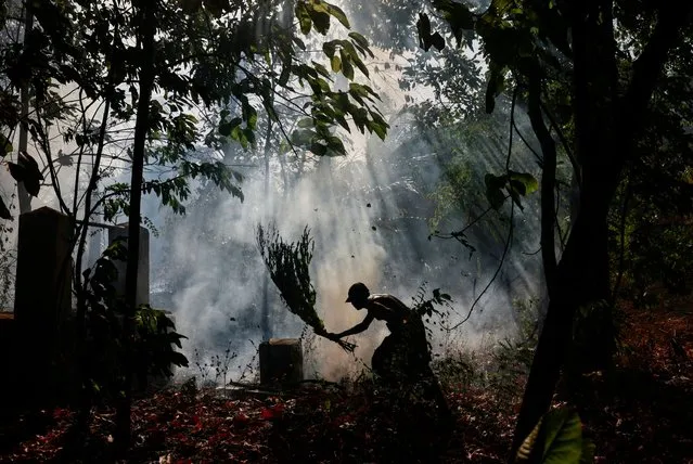 A farmer tries to stop a fire in an abandoned farming land amid a drought in Anamaduwa, Sri Lanka on August 20,2023. (Photo by Dinuka Liyanawatte/Reuters)