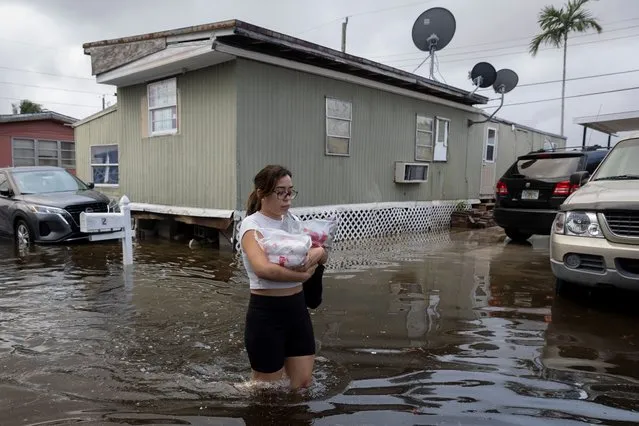 A woman walks in a flooded street at a trailer park community in Hialeah, Florida on November 16, 2023. (Photo by Marco Bello/Reuters)
