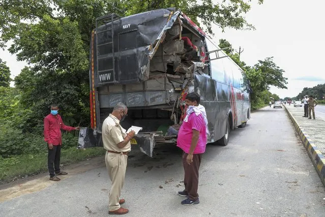A police officer takes notes next to a parked bus onto which a truck struck overnight in Barabanki, Uttar Pradesh state, India, Wednesday, July 28, 2021. Police say a truck struck a group of laborers sleeping under the parked bus on the side of a highway in northern India, killing more than a dozen of them. (Photo by Sumit Kumar/AP Photo)
