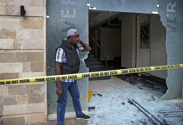 A plain-clothed member of security forces stands by the entrance to a hallway in which an unexploded grenade lies, at a hotel complex in Nairobi, Kenya Tuesday, January 15, 2019. Terrorists attacked an upscale hotel complex in Kenya's capital Tuesday, sending people fleeing in panic as explosions and heavy gunfire reverberated through the neighborhood. (Photo by Ben Curtis/AP Photo)