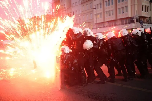 Turkish riot police officers take cover as Kurdish protesters shoot fireworks at them during clashes in central Istanbul on December 7, 2013. Two protesters were killed on December 6 in armed clashes with Turkish police that erupted over claims that Kurdish rebel cemeteries had been destroyed, local media reported. Some 30 masked men in a group of around 150 demonstrators hurled Molotov cocktails and hand grenades at security forces in the Yuksekova district of Kurdish-dominated southeastern Turkey, the Dogan News Agency said. (Photo by Bulent Kilic/AFP Photo)
