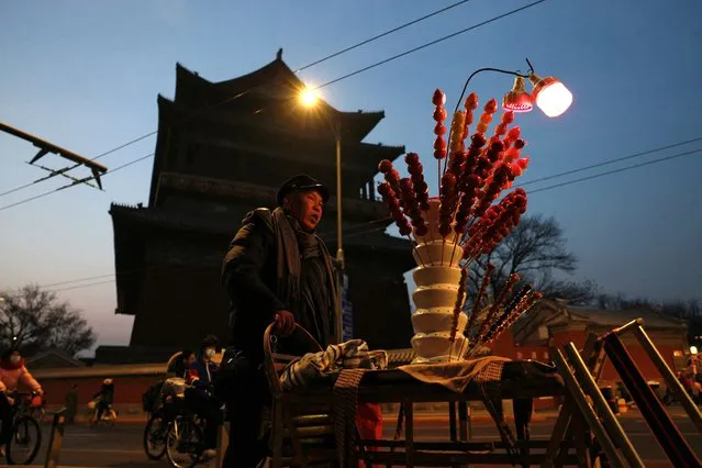 A vendor pushes a cart selling sugar-coated haws at the Drum Tower in Beijing, China on December 5, 2023. (Photo by Tingshu Wang/Reuters)