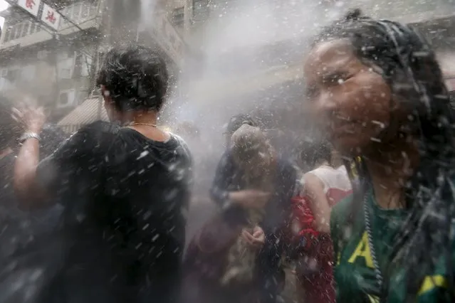 Revellers take part in a water fight during Songkran Festival celebrations at Kowloon City district, known as Little Thailand as there is large number of restaurants and shops run by Thais, April 12, 2015. (Photo by Tyrone Siu/Reuters)